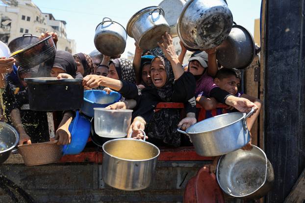 Palestinians wait to receive food from a charity kitchen, in Gaza City