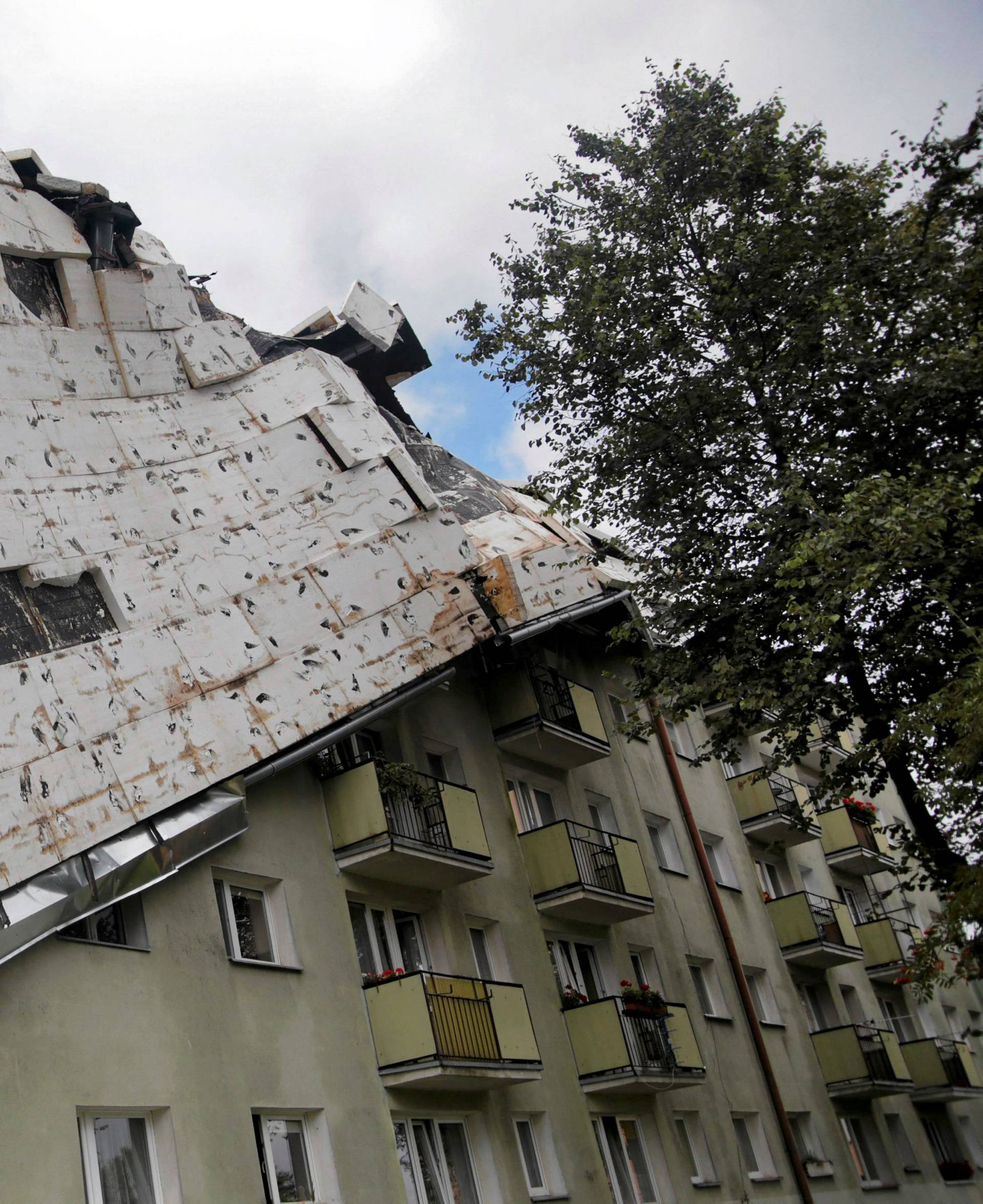 A roof destroyed by a storm hangs from an apartment building in Bydgoszcz