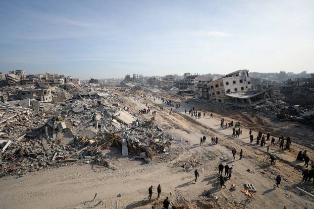 Displaced Palestinians walk past the rubble as they attempt to return to their homes, in the northern Gaza Strip