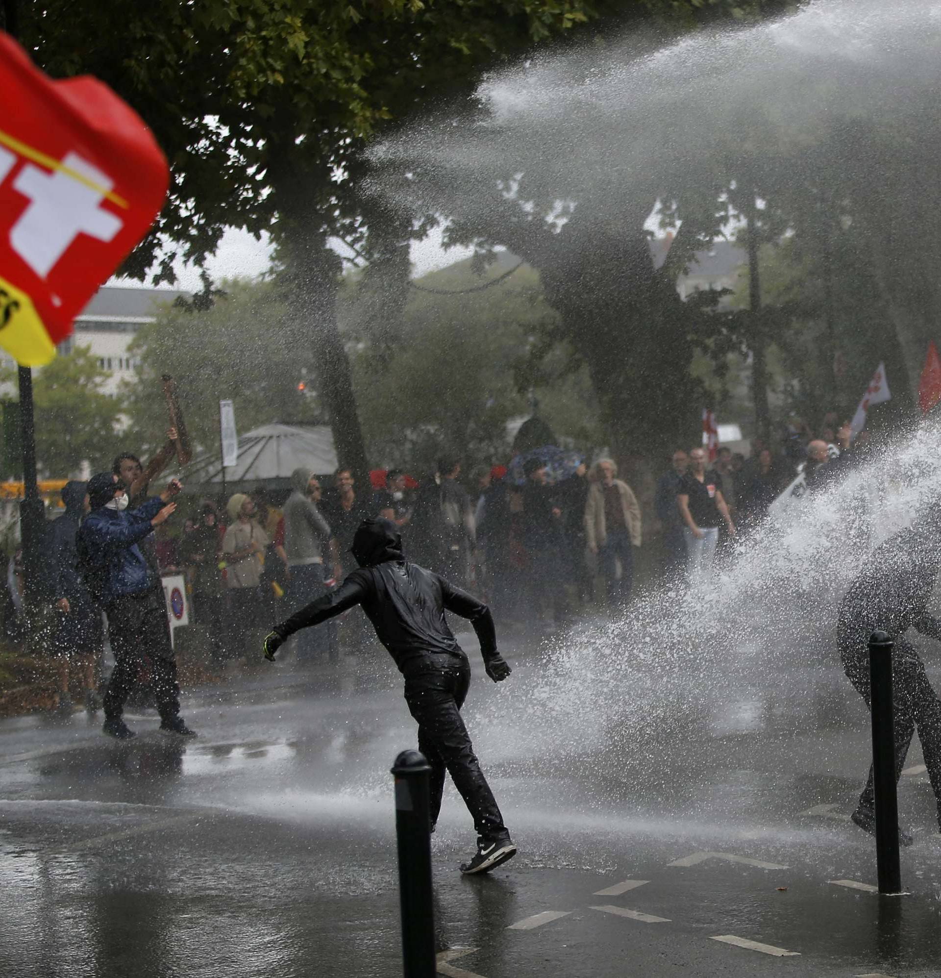 Demonstrators are sprayed by a water canon during clashes with French riot police at a march in Nantes