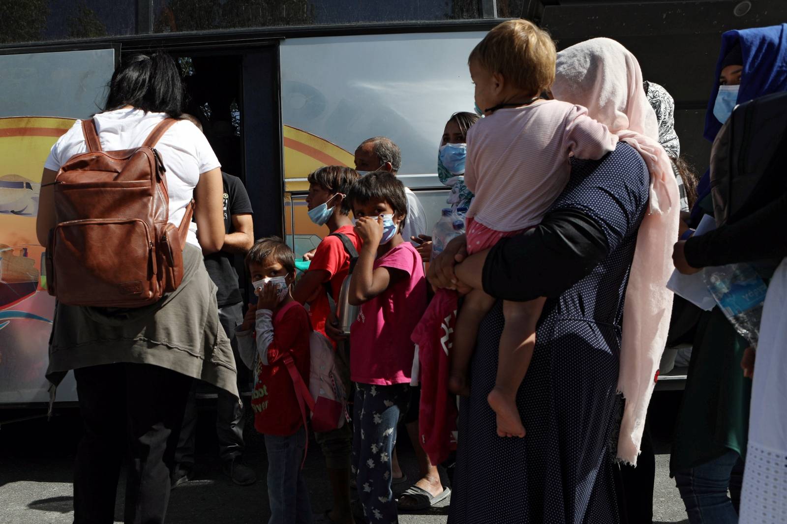 Refugees and migrants from the destroyed Moria camp board a bus to the port, from where they will be transferred to the mainland, on the island of Lesbos