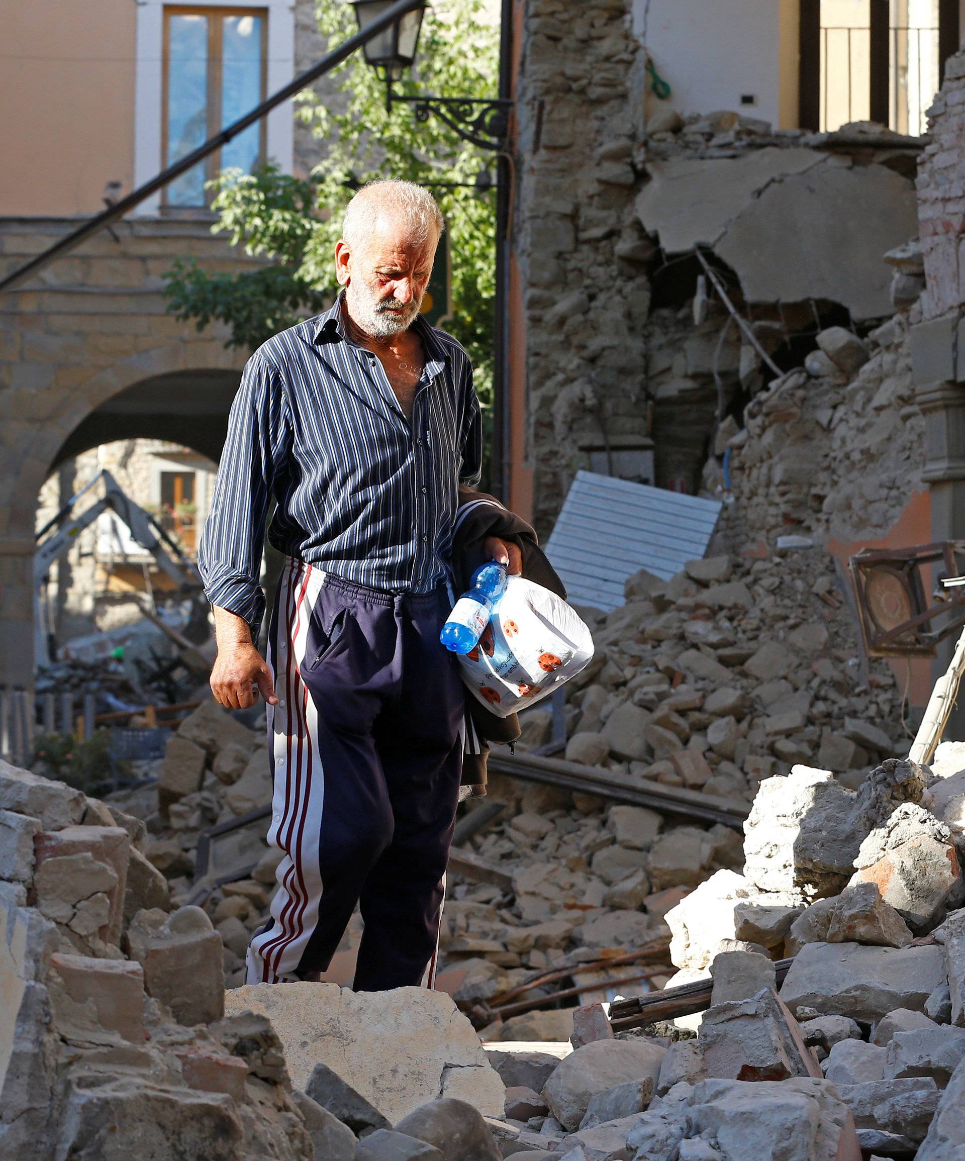 A man walks through rubble following an earthquake in Amatrice