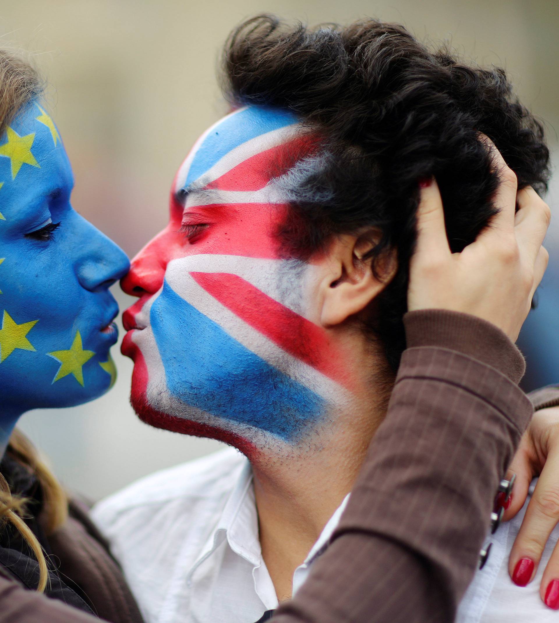 Two activists with the EU flag and Union Jack painted on their faces kiss each other in front of Brandenburg Gate to protest against Brexit in Berlin