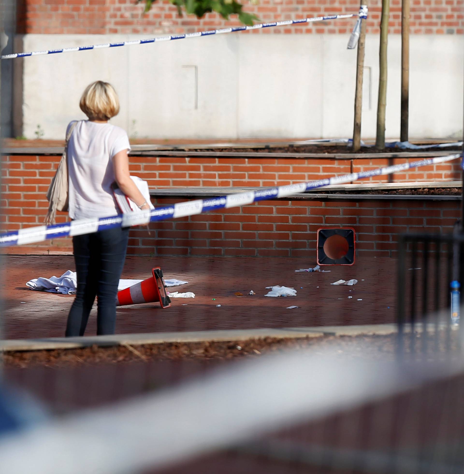 A woman stands at the site where a machete-wielding man injured two female police officers before being shot outside the main police station in Charleroi