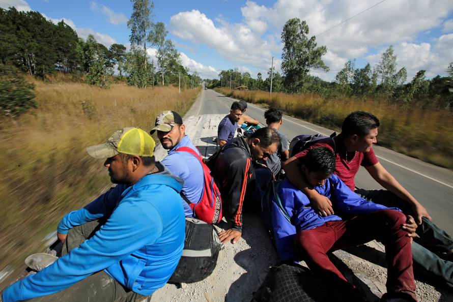 Hondurans, part of a new caravan of migrants travelling towards the United States, ride in a trailer as they hitch a ride in Cucuyagua