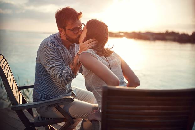 beardy caucasian young guy kissing his woman by the sea