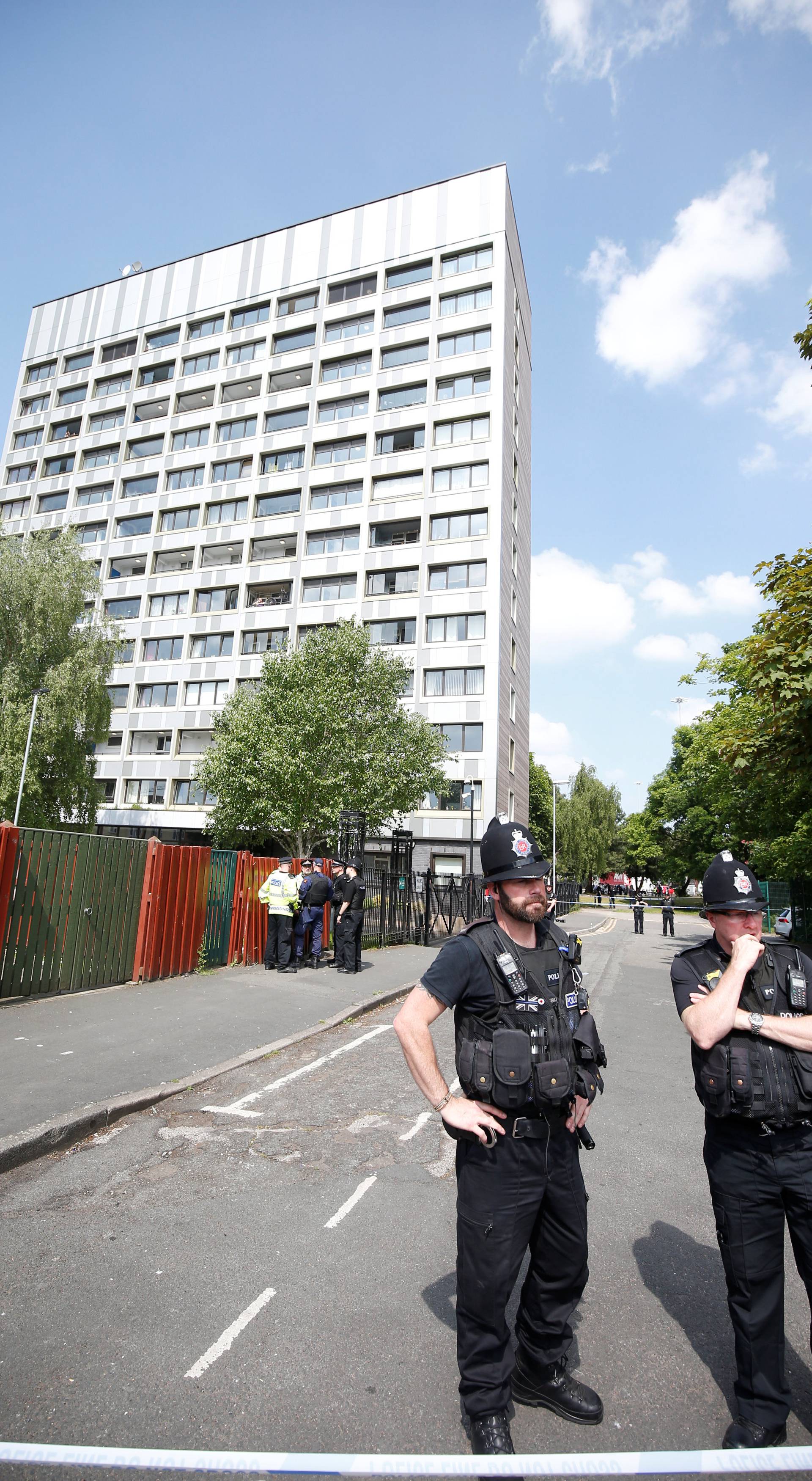 Police officers stand outside flats in Hulme, Manchester