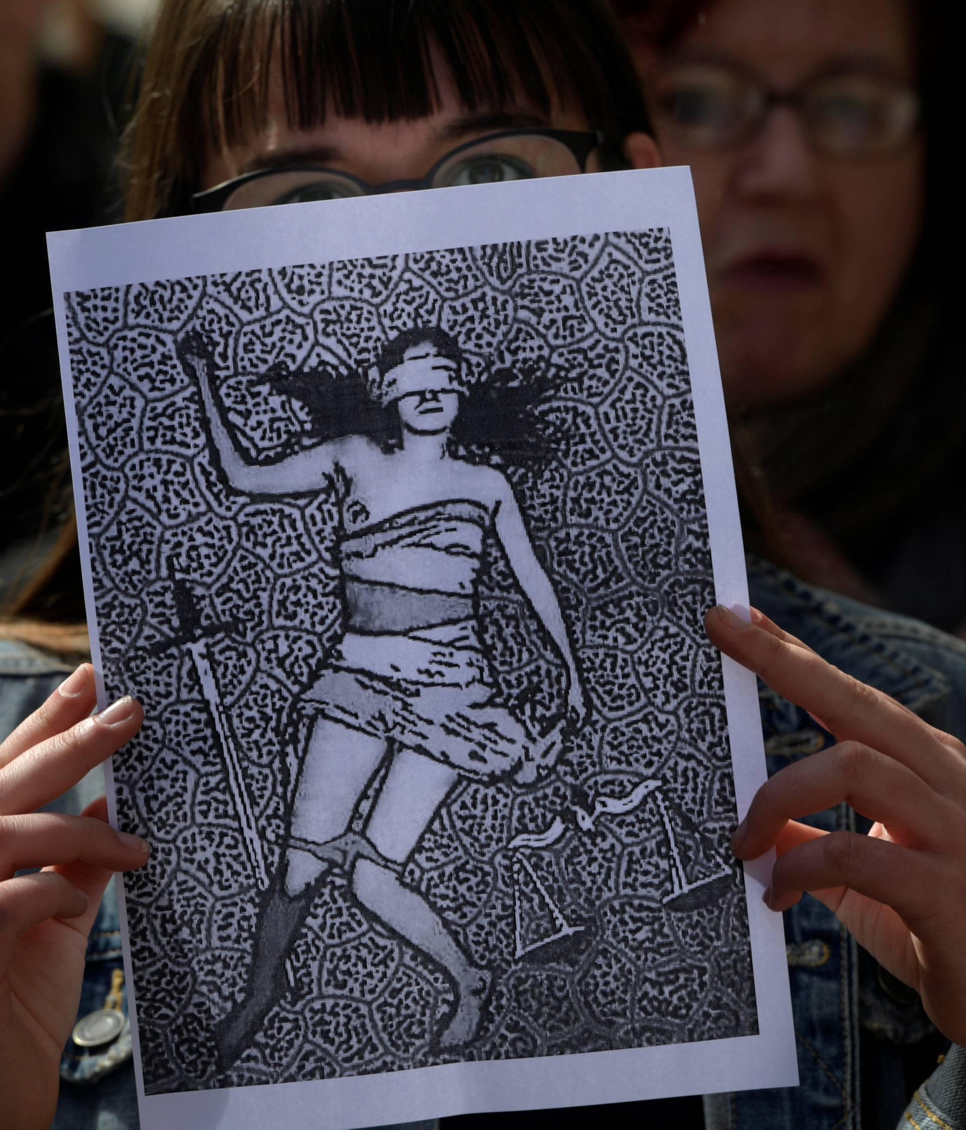 A woman holds up a picture as other shout slogans during a protest outside the courts of Aviles