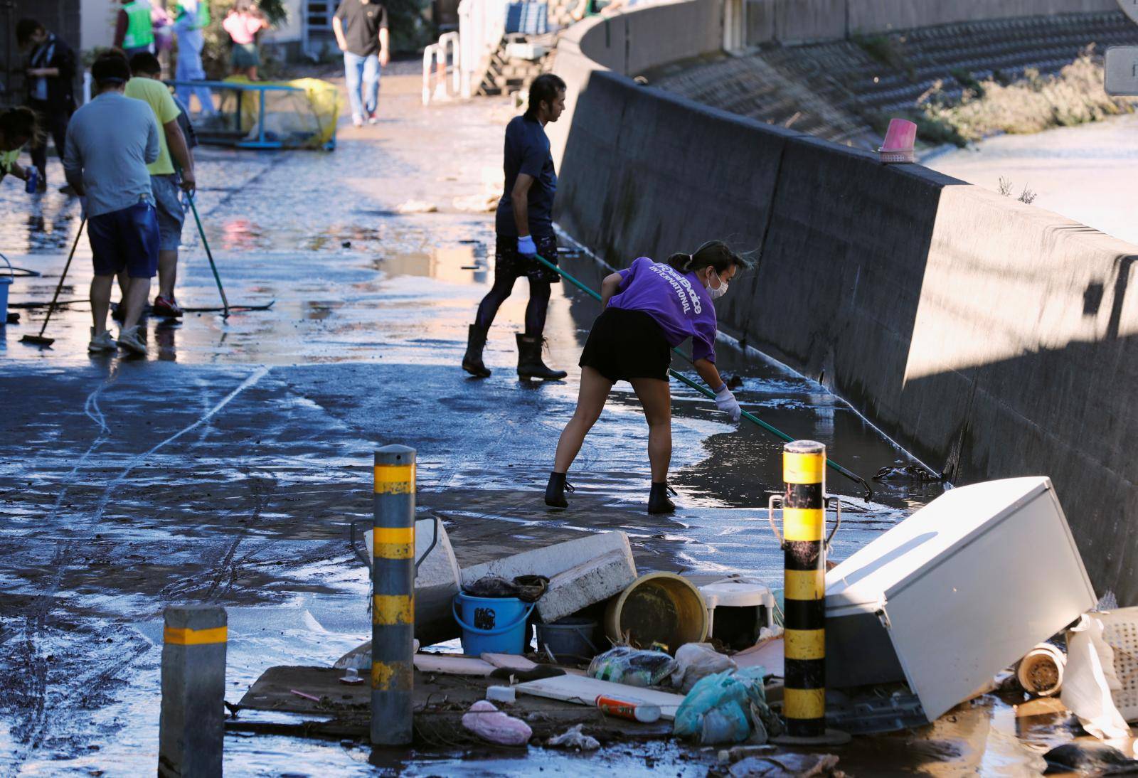 People clean up debris after floodwaters caused by Typhoon Hagibis receded in a residential area, in Kawasaki, Japan,