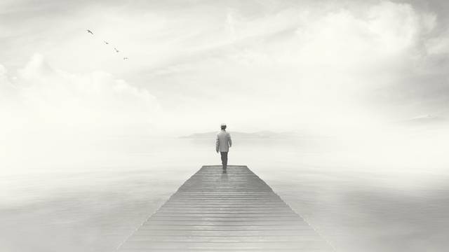 Man walking on a boardwalk in the fog