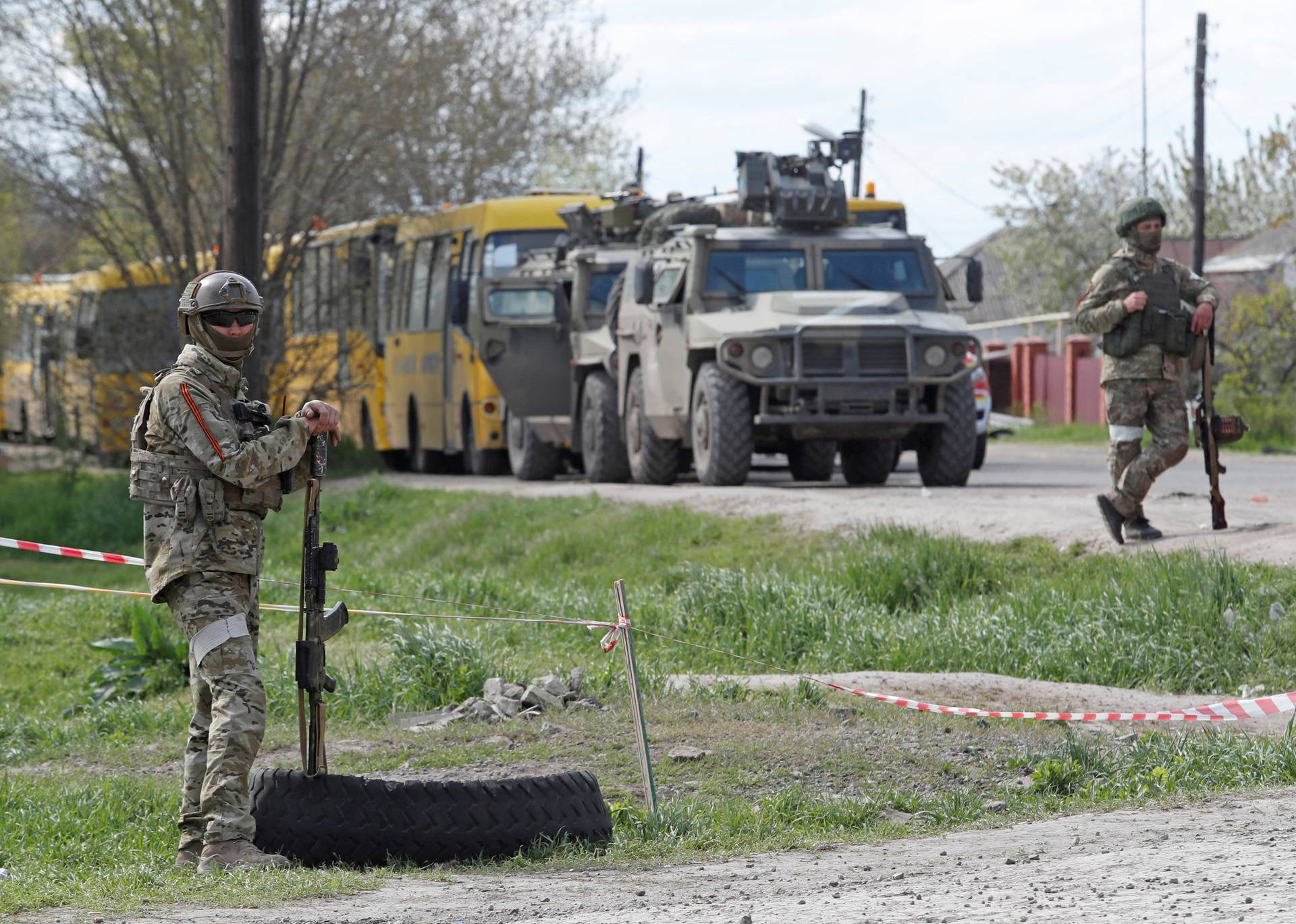 Service members of pro-Russian troops stand guard near a temporary accommodation centre for evacuees in Bezimenne