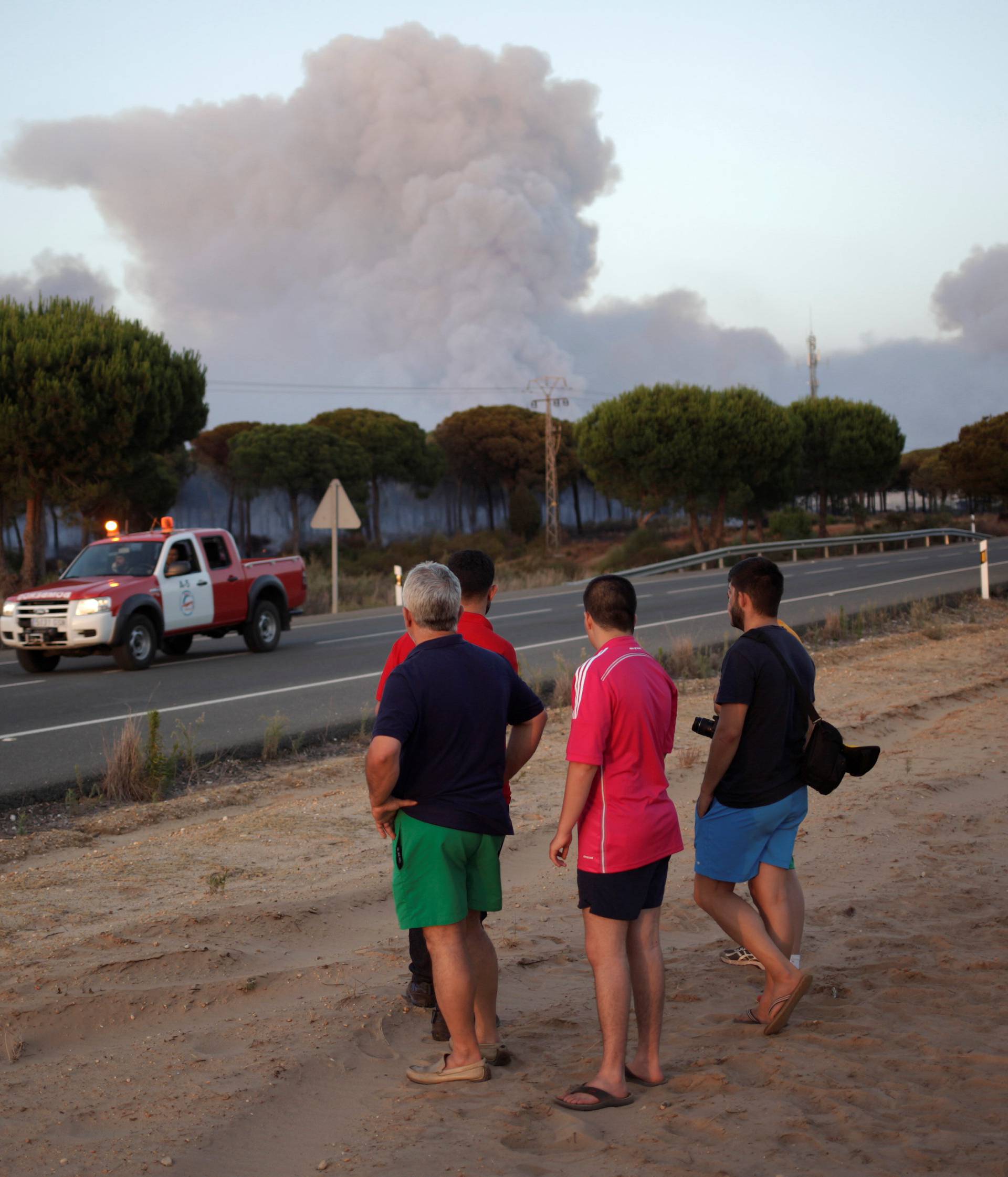 People look at smoke from a forest fire near Donana National Park in Mazagon