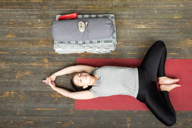 woman practicing yoga in Reclined Butterfly exercise, supta baddha konasana