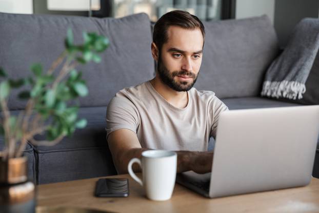 Concentrated young man using laptop computer.