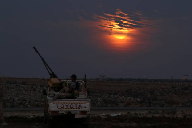 A Free Syrian army fighter sits on a pick-up truck mounted with a weapon, as the supermoon partly covered by clouds is seen in the background, in the west of the rebel-held town of Dael