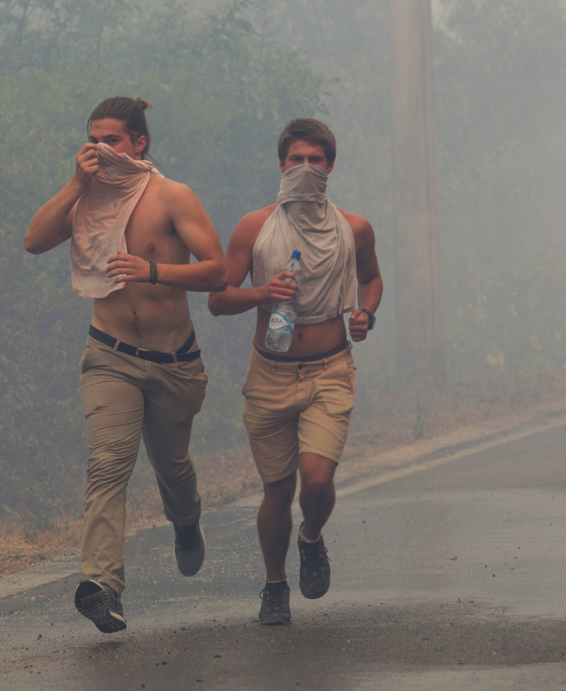 Tourists run through smoke during a forest fire at Lustica peninsula near Tivat