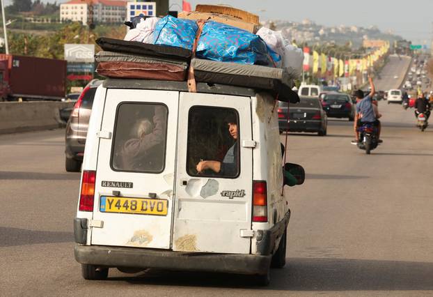 A displaced person looks out from a van as people make their way as they return to their homes after a 10-day ceasefire between Lebanon and Israel went into effect, near Sidon