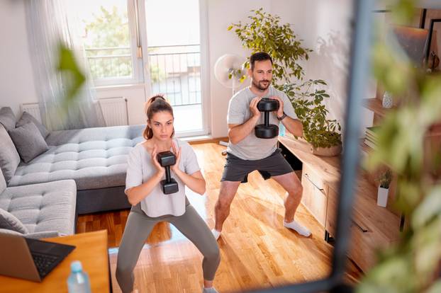 Couple,Working,Out,At,Home,Doing,Squats,Using,Dumbbells