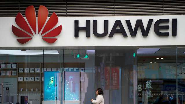 FILE PHOTO: A woman walks by a Huawei logo at a shopping mall in Shanghai