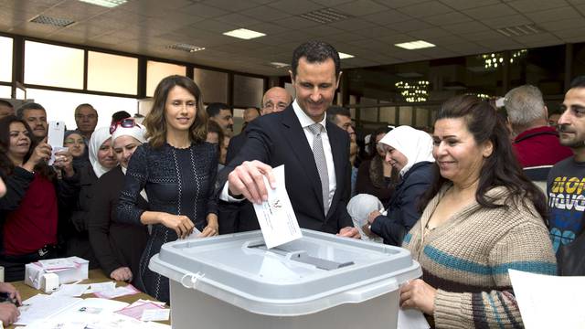 Syria's President Bashar al-Assad casts his vote next to his wife Asma inside a polling station during the parliamentary elections in Damascus