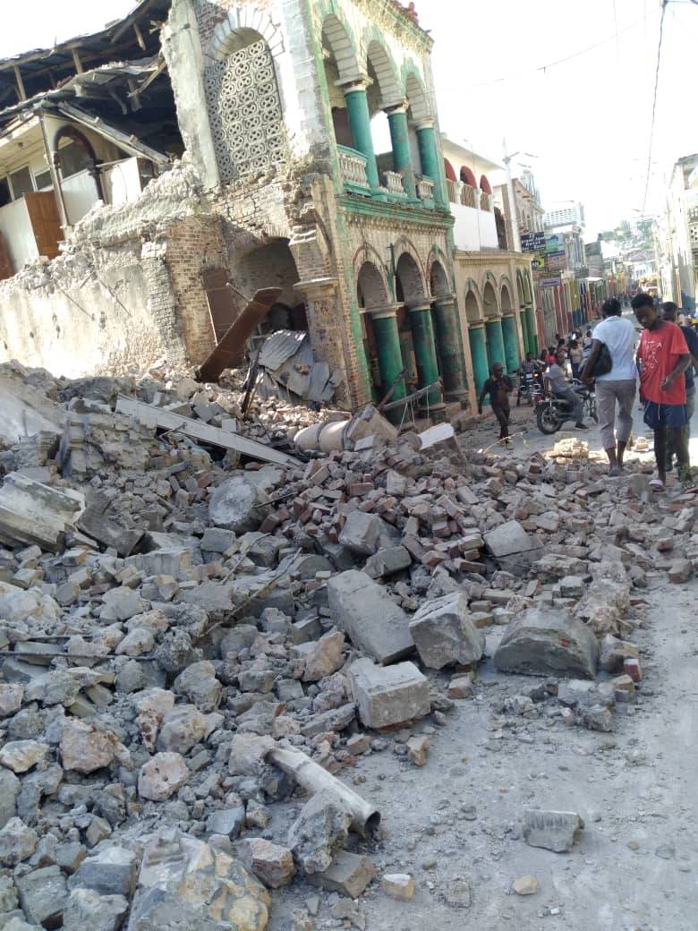 People walk next to debris following an earthquake in Jeremie