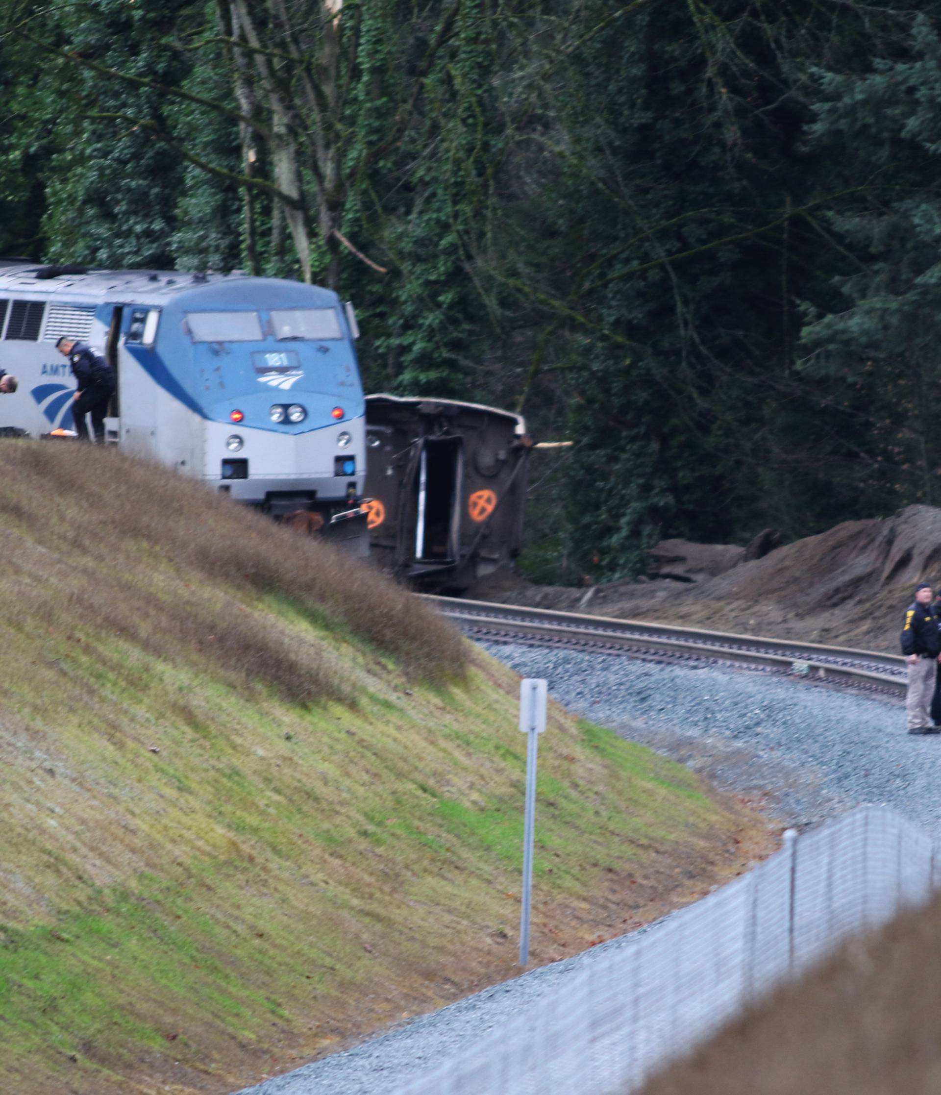 First responders and investigators are seen near the scene of an Amtrak passenger train which derailed on a bridge over the I-5 in DuPont