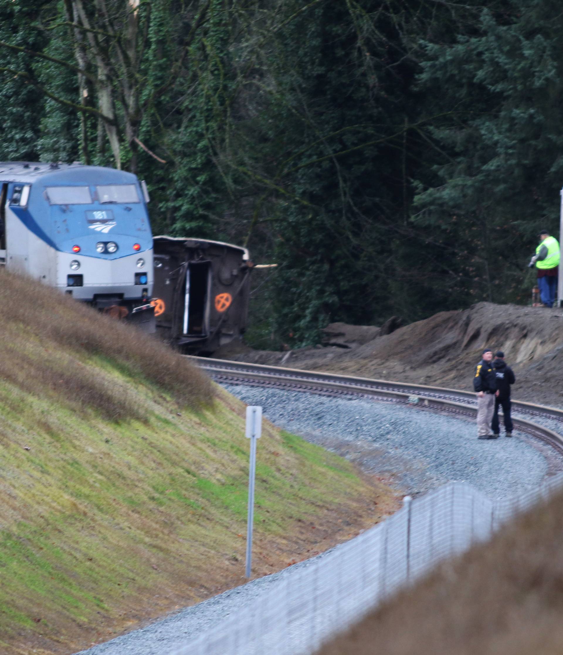 First responders and investigators are seen near the scene of an Amtrak passenger train which derailed on a bridge over the I-5 in DuPont