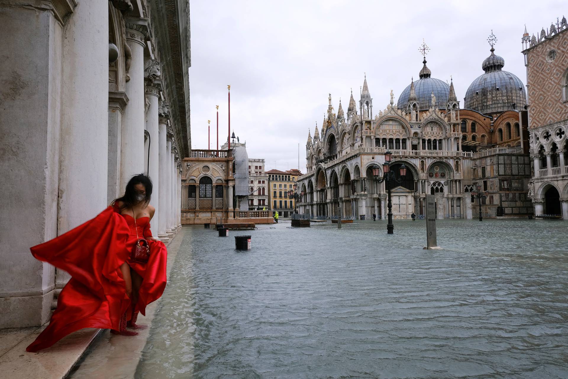 A woman stands in flooded St. Mark's Square during high tide as the flood barriers known as Mose are not raised, in Venice