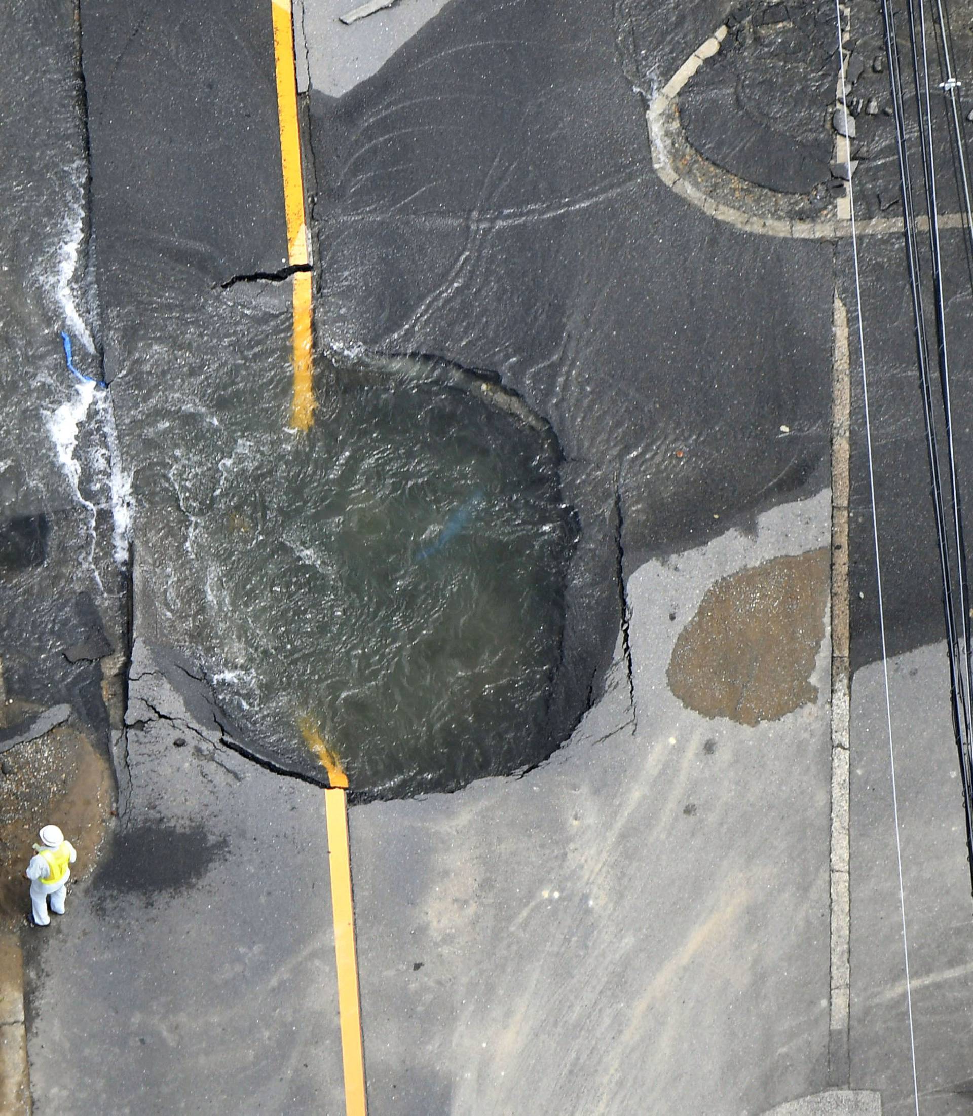 Water flows out from cracks in a road damaged by an earthquake in Takatsuki