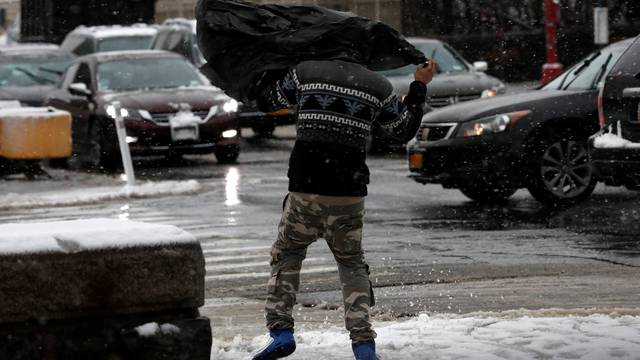 A man struggles in the wind beneath a plastic bag as he walks during a snowstorm in upper Manhattan in New York City