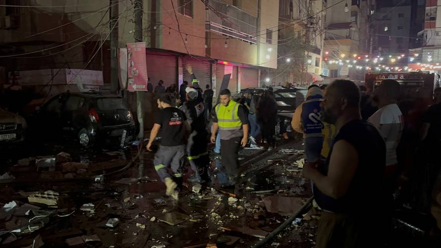 People gather near a building where a floor caught fire following an Israeli strike, in which the Israeli military said, it killed Hamas commander Hassan Farhat, in Sidon