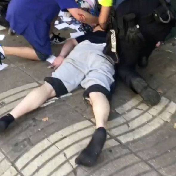 Police officer helps injured man after a van crashed into pedestrians near the Las Ramblas avenue in central Barcelona