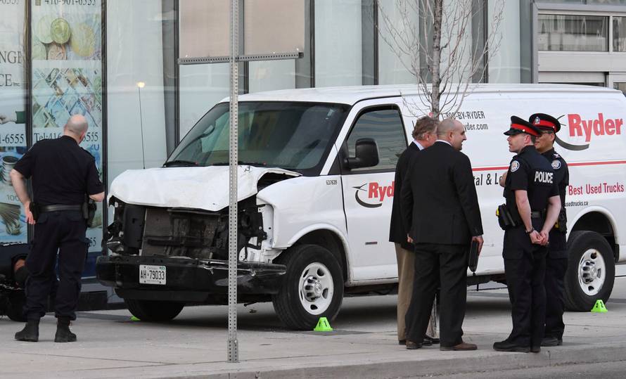 Investigators view a damaged van seized by police after multiple people were struck at a major intersection northern Toronto