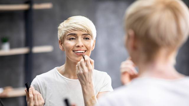 Middle-Aged Lady Applying Lipstick On Lips Standing In Bathroom