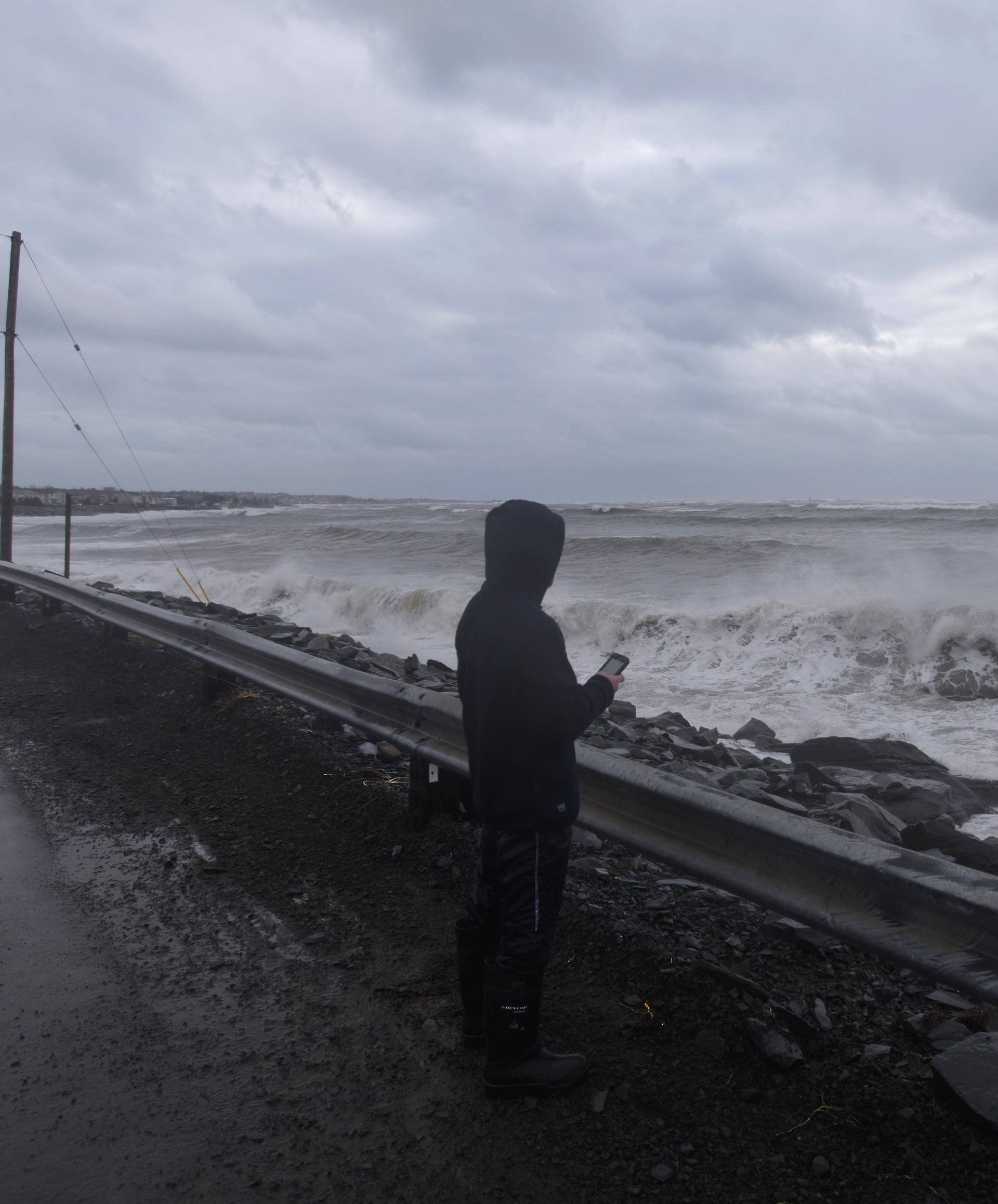 A man films storm surge from the Atlantic Ocean during Storm Grayson in Halifax