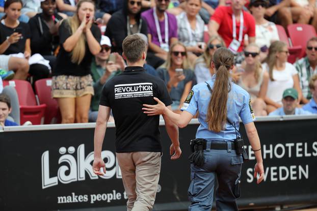 A man is escorted out of the court after raising his right fist during the ATP tennis tournament Swedish Open semi-final match between Fernando Verdasco of Spain and David Ferrer of Spain, in Bastad