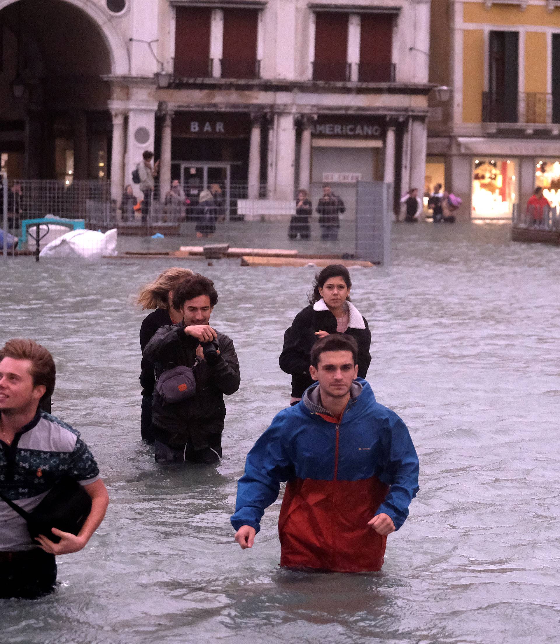 People walk in a flooded Saint Mark Square during a period of seasonal high water in Venice