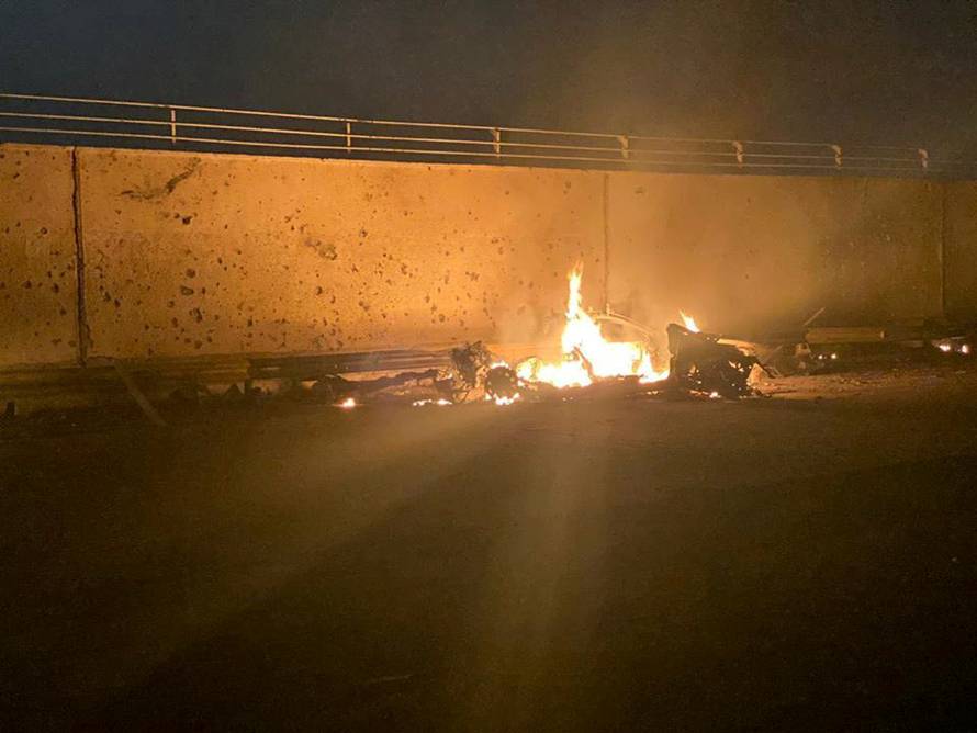 Burning debris are seen on a road near Baghdad International Airport