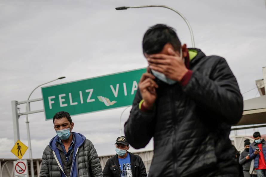 Migrants walk across the Paso del Norte international border bridge after being deported from the United States, in Ciudad Juarez