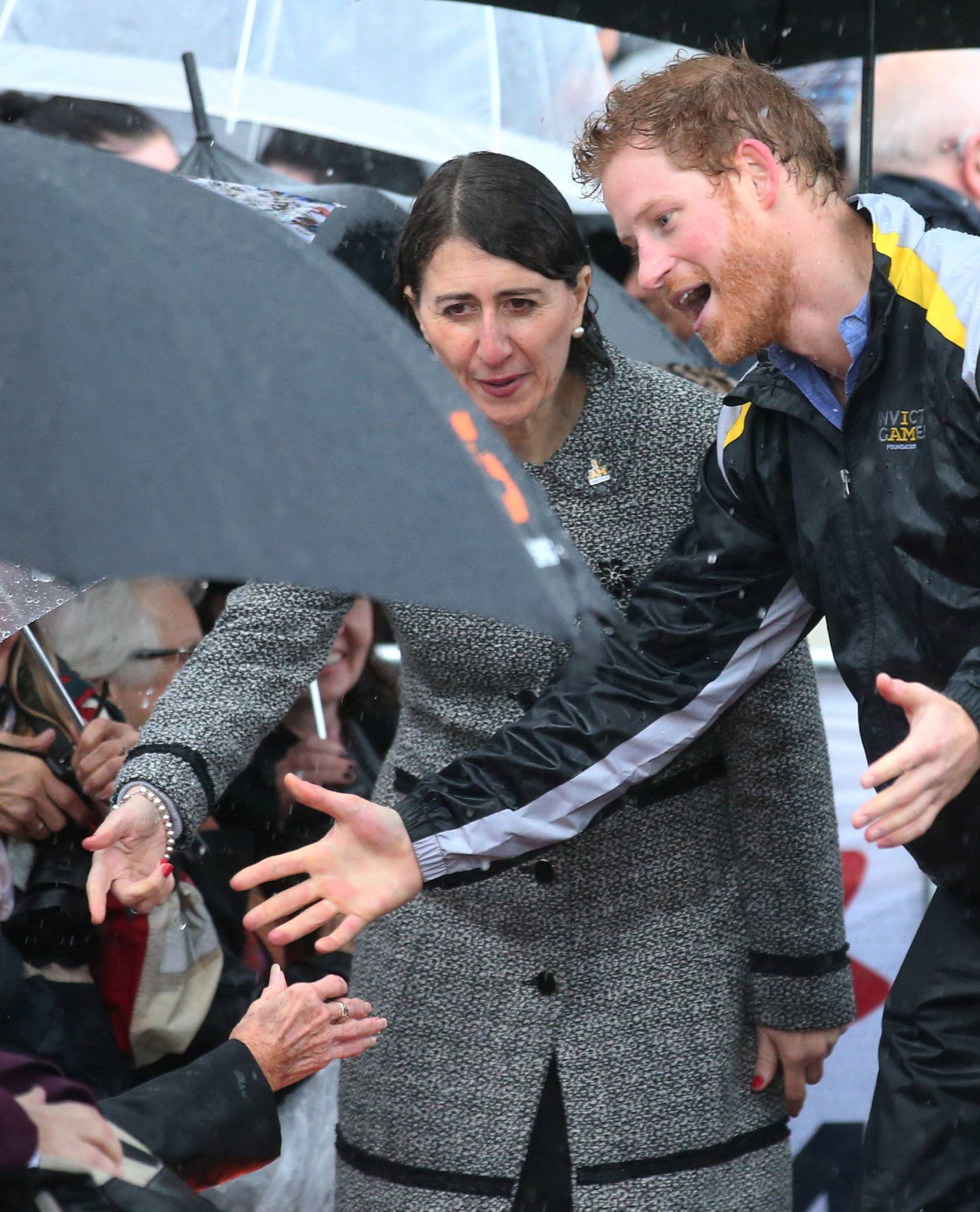 Britain's Prince Harry reacts before hugging Daphne Dunne, 97, during a walk around The Rocks district in rainy Sydney, Australia