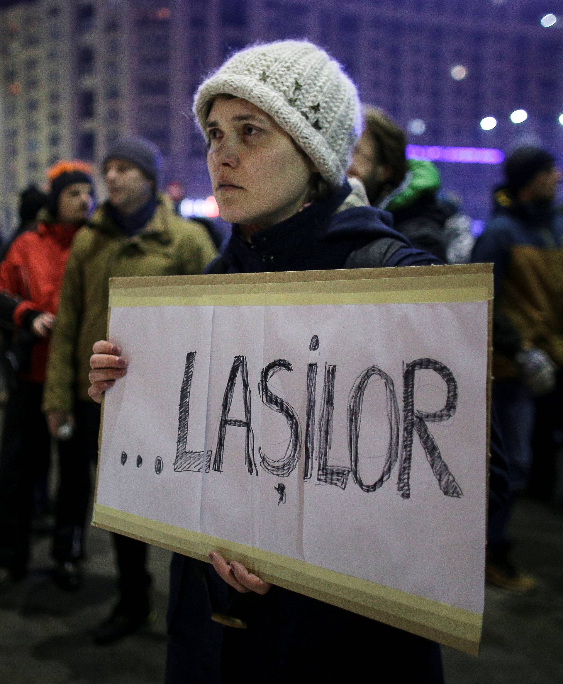 A woman holds a sign reading "Cowards"  during a protest after the Romanian government decriminalized some graft offenses late on Tuesday in Bucharest, Romania