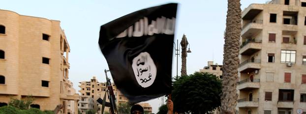 FILE PHOTO: A member loyal to the ISIL waves an ISIL flag in Raqqa