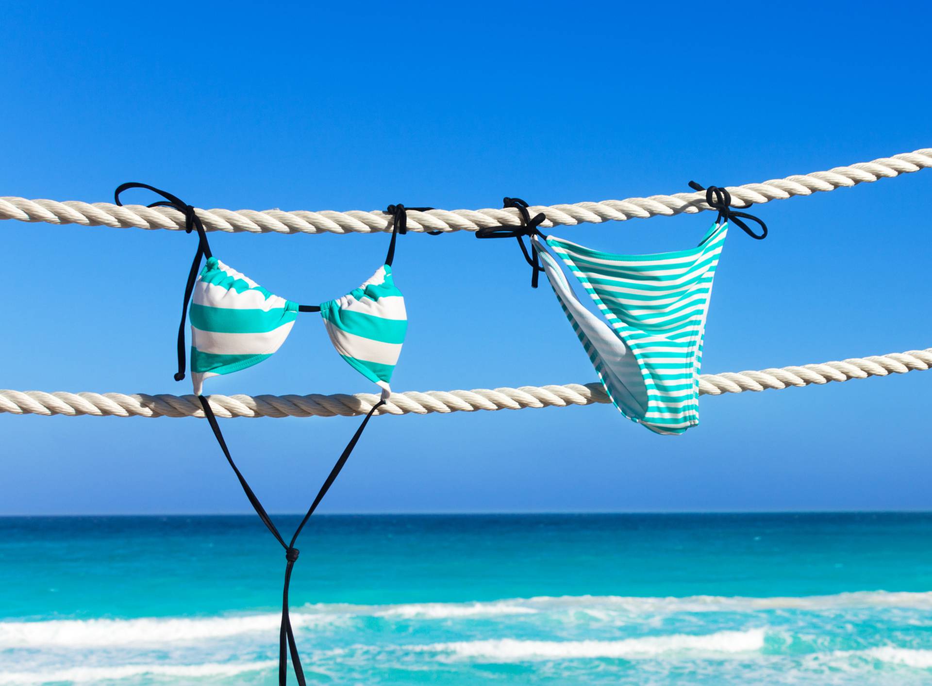 Blue woman's swimming suit hanging on white ropes