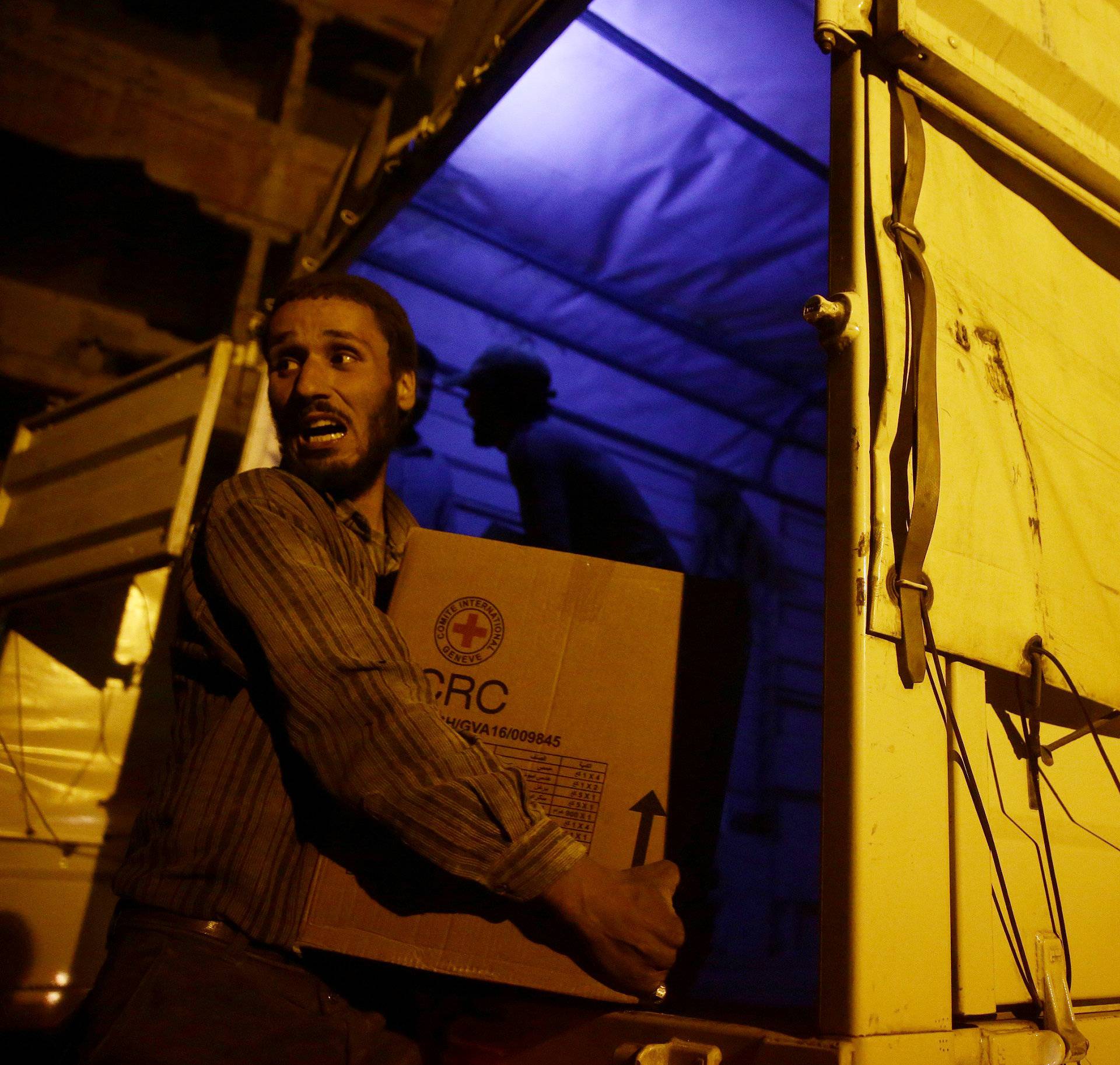 Relief workers unload parcels of humanitarian aid in the rebel-held besieged Syrian town of Douma