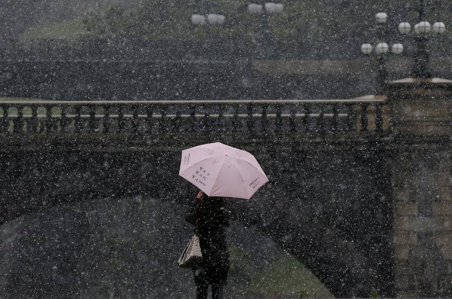 A tourist takes photos during the first November snowfall in 54 years in Tokyo