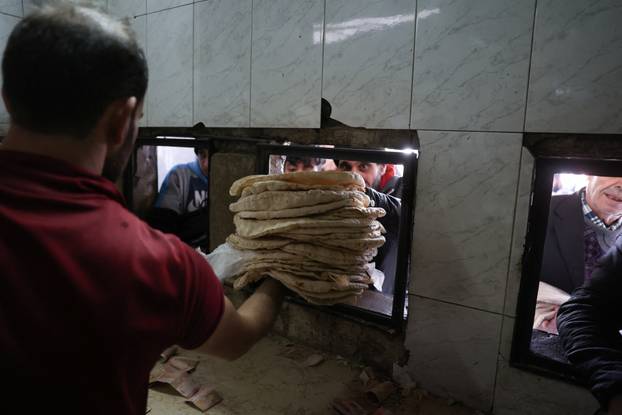 People queue to buy bread in Damascus