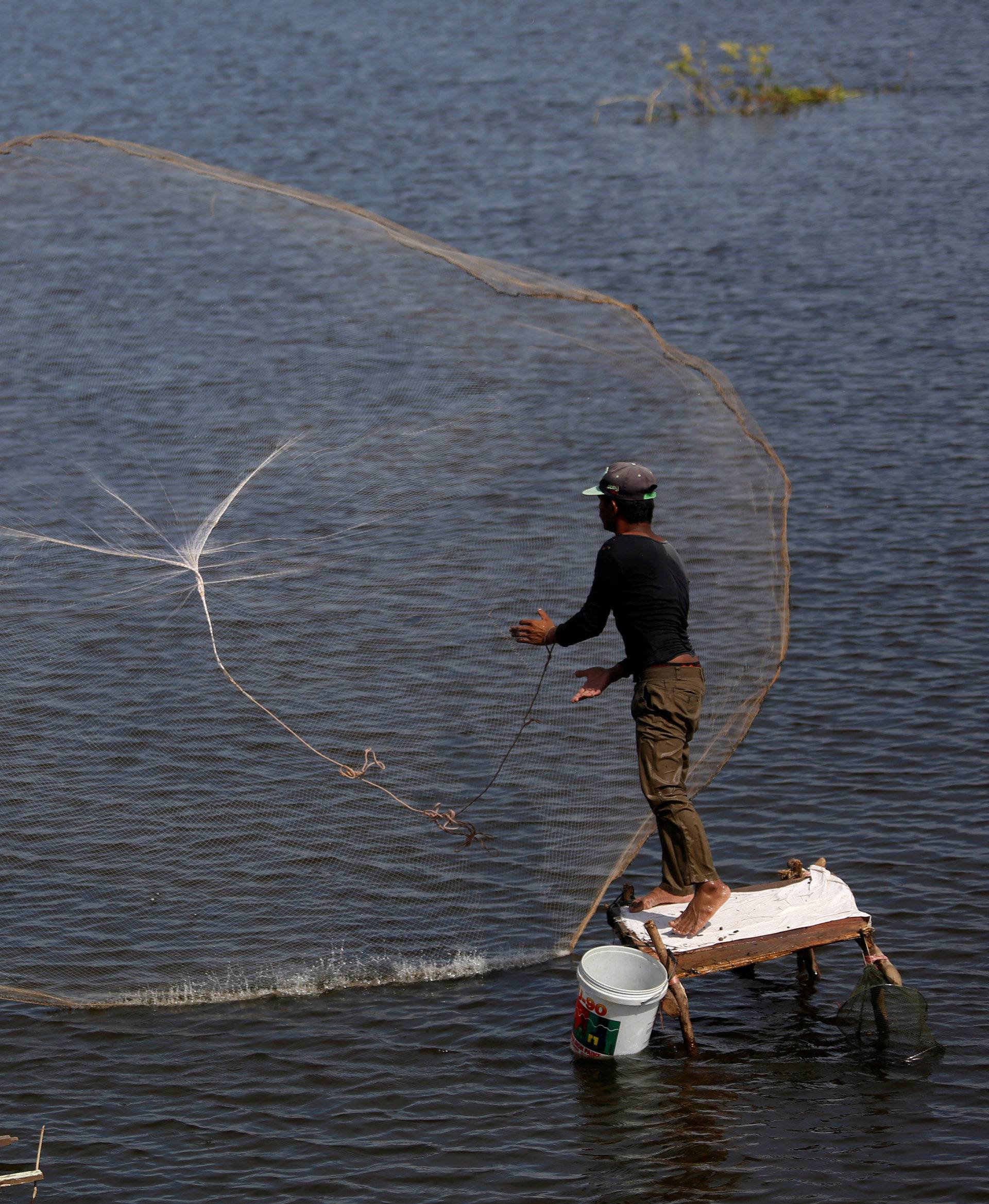 A man casts a fishing net into a lake in Kandal province, Cambodia
