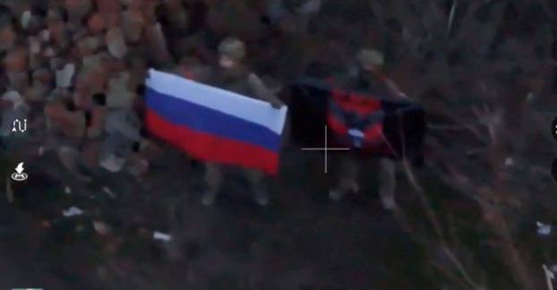 A soldier holds up a Russian flag in Kurakhove, Donetsk Region