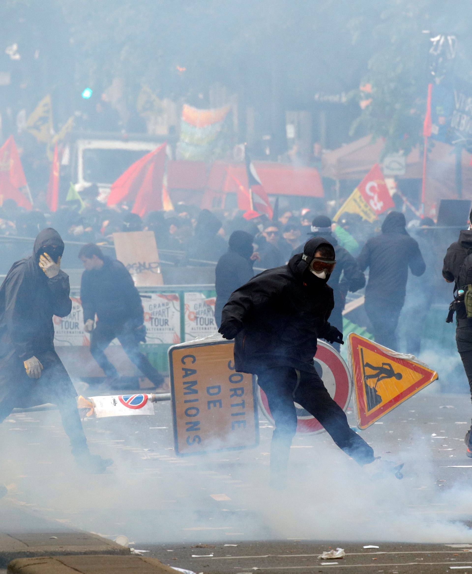 Tear gas floats around masked protesters during clashes with French CRS riot police at the May Day labour union rally in Paris