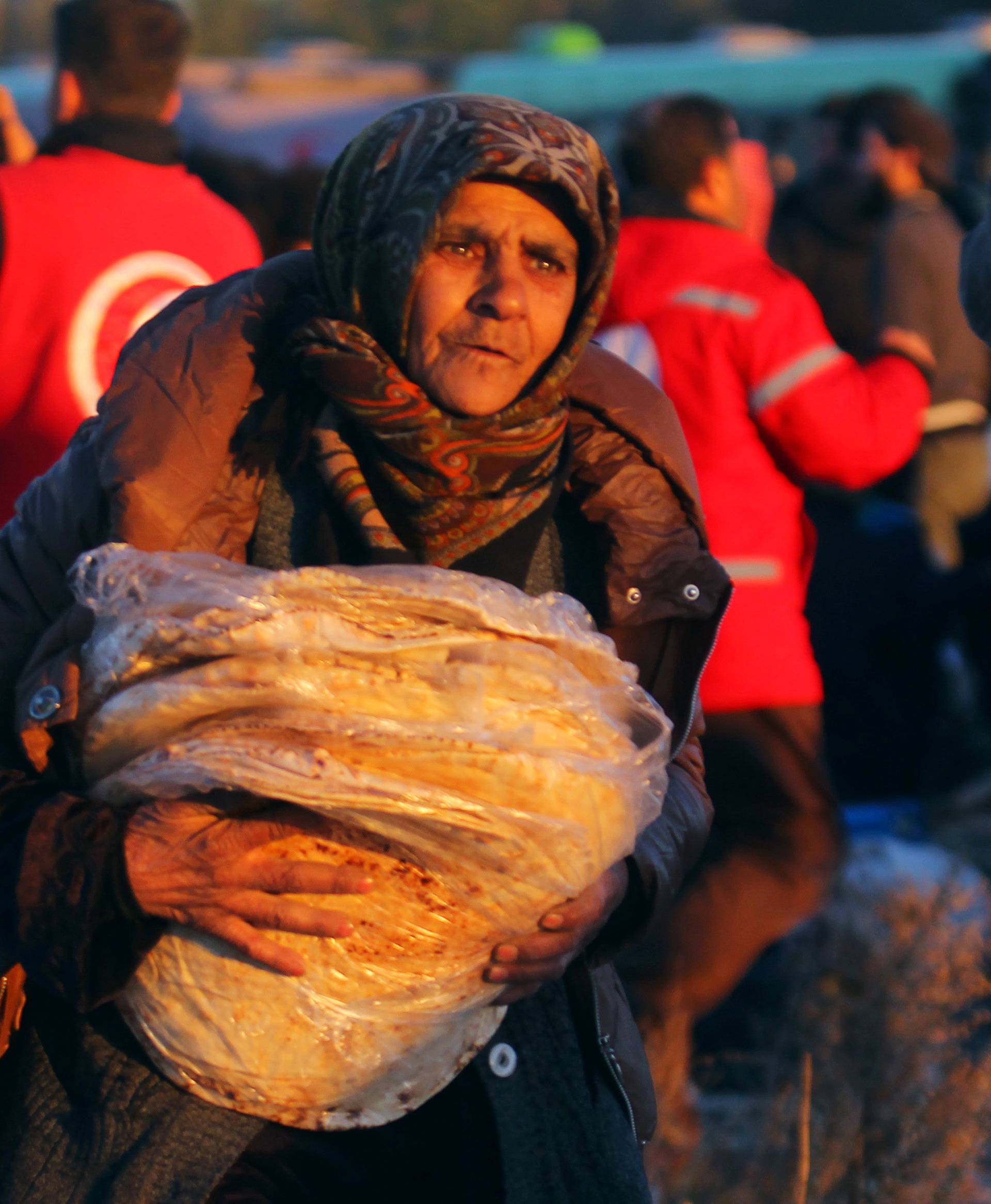 An evacuee from rebel-held east Aleppo carries bread upon her arrival with others at the town of al-Rashideen